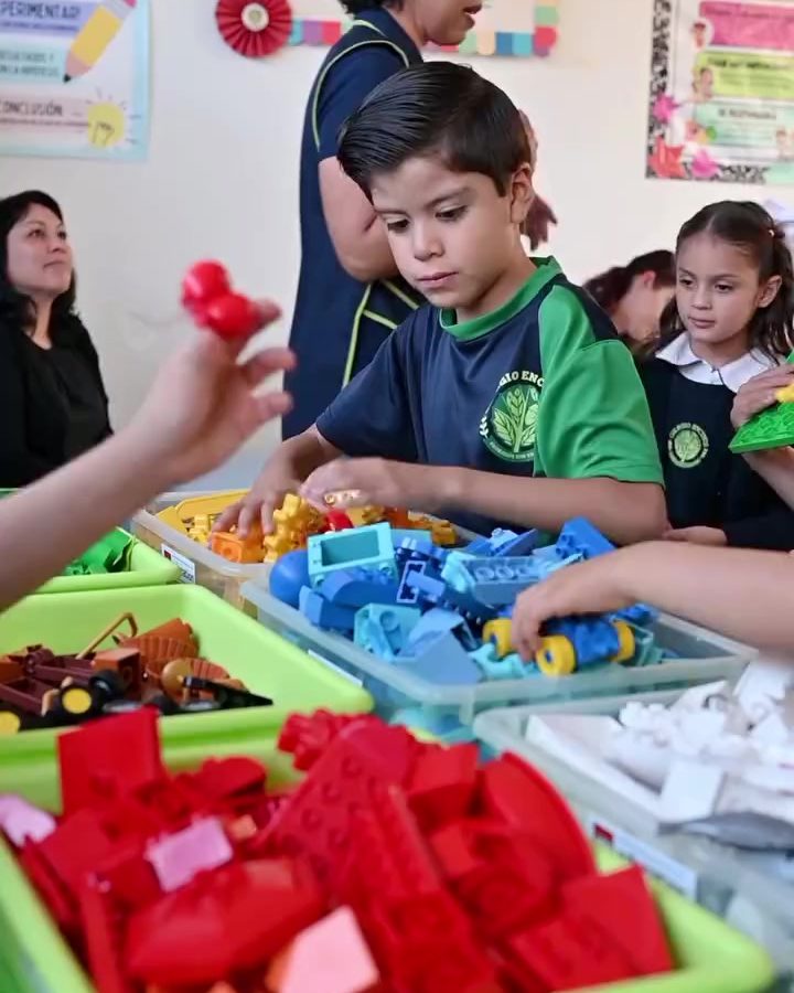 Maestra de Colegio Encinos ayudando a dos niños a construir con bloques rojos y azules