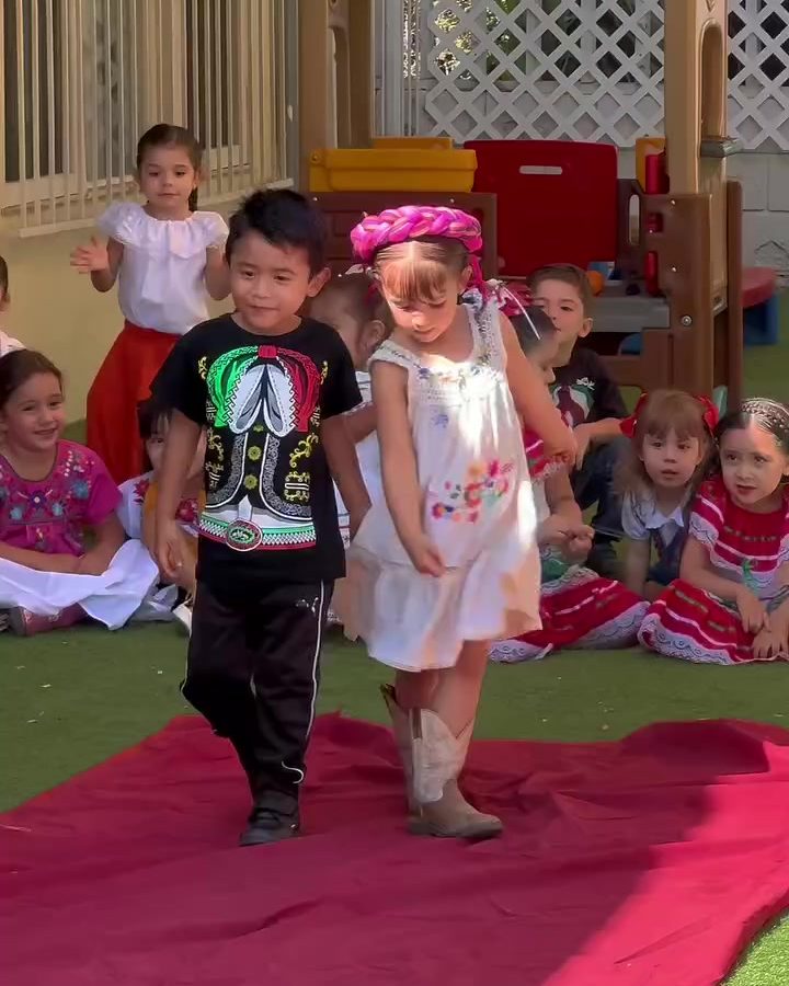 Niños de maternal caminando sobre una alfombra roja en la pasarela de trajes típicos