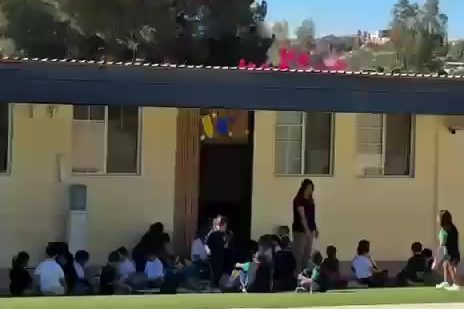 Patio de Colegio Encinos con techumbres, pinos y los cerros de Tecate al fondo