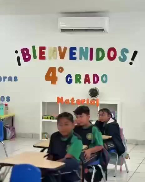 Salón de cuarto grado de primaria con letrero de bienvenida y alumnos sentados en sus bancas